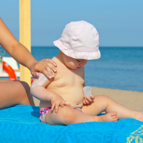 Baby wird mit Sonnencreme eingecremt